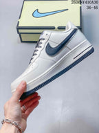 Side view of the white low-top sneaker with a dark navy Swoosh and outsole