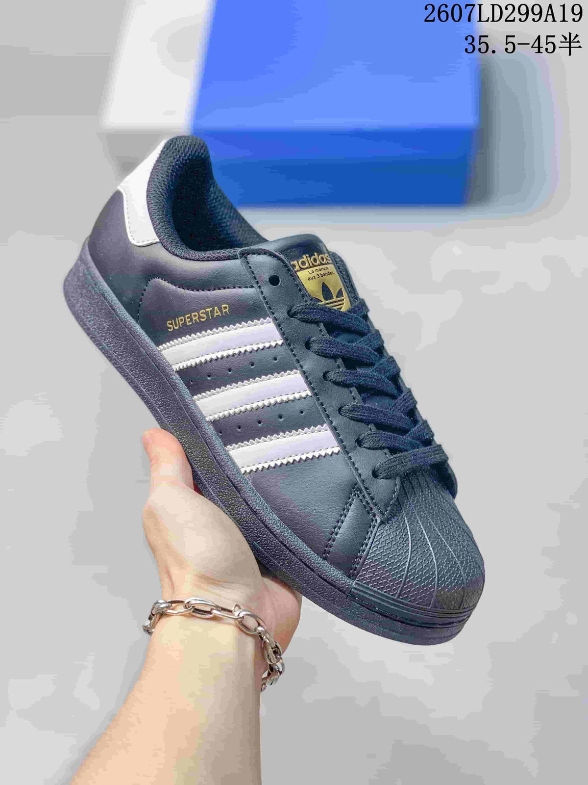 Dark adidas Superstar sneaker with white serrated stripes, dark laces and shell toe.