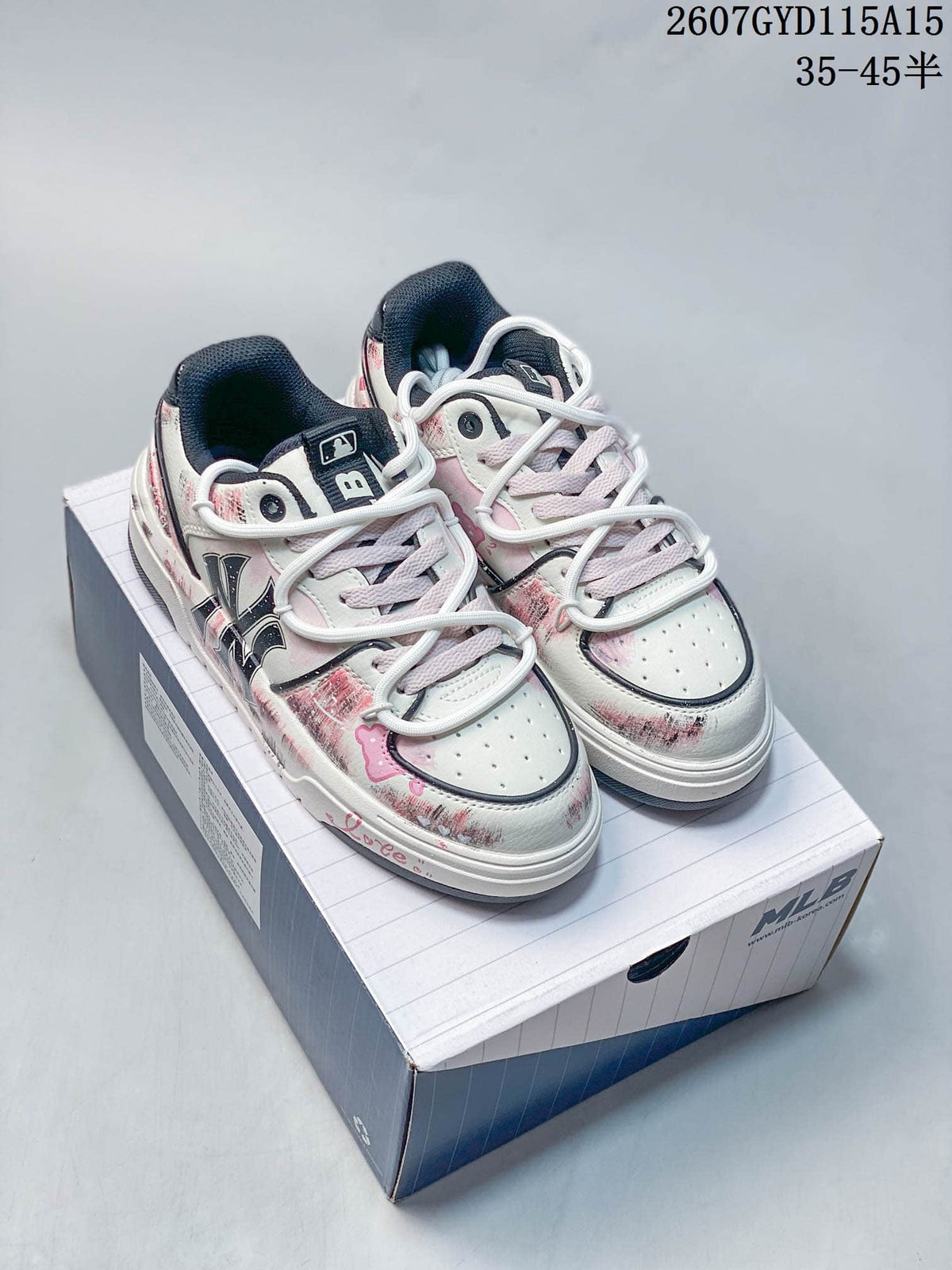 Pair of white and pale pink MLB sneakers with distressed graffiti graphics displayed on a branded shoe box.