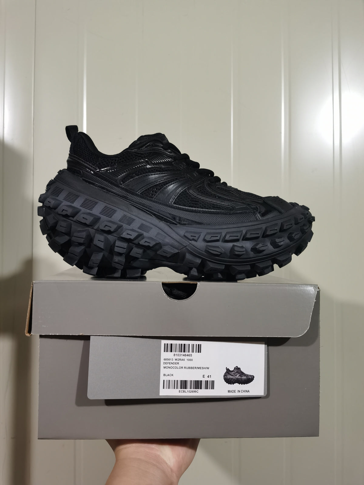 Black chunky sneaker displayed on its shoe box; the box label reads Defender, Monocolor Rubber/Mesh/W, Black, and E 41.