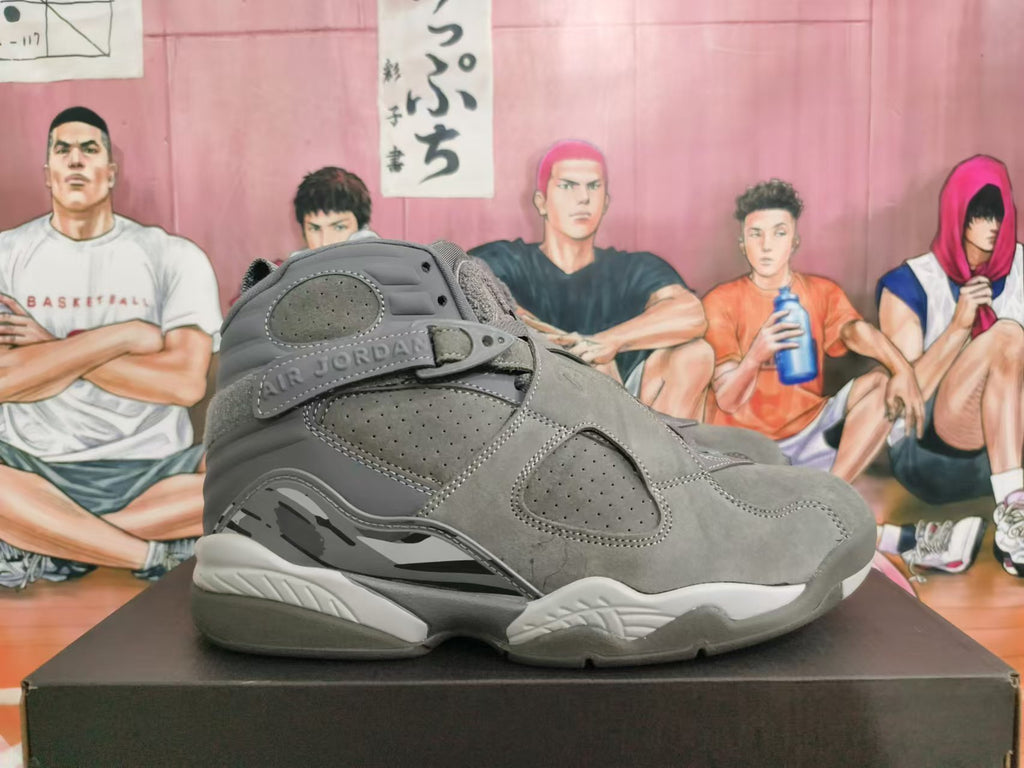 Side view of a grey Jordan high-top sneaker with perforated panels, a cross strap, and contrasting midsole details.