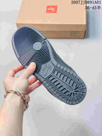 Underside of a dark gray Nike Dunk Low sneaker showing the patterned outsole
