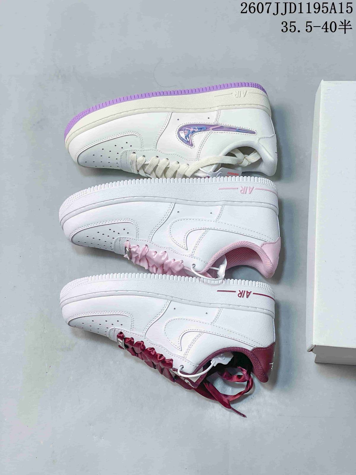 Top-down view showing three white Nike Air Force 1 colorways with burgundy, pink and purple accent details beside shoe boxes.