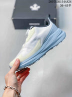 Side profile showing the white upper, pale yellow accents, light blue midsole, and textured outsole.