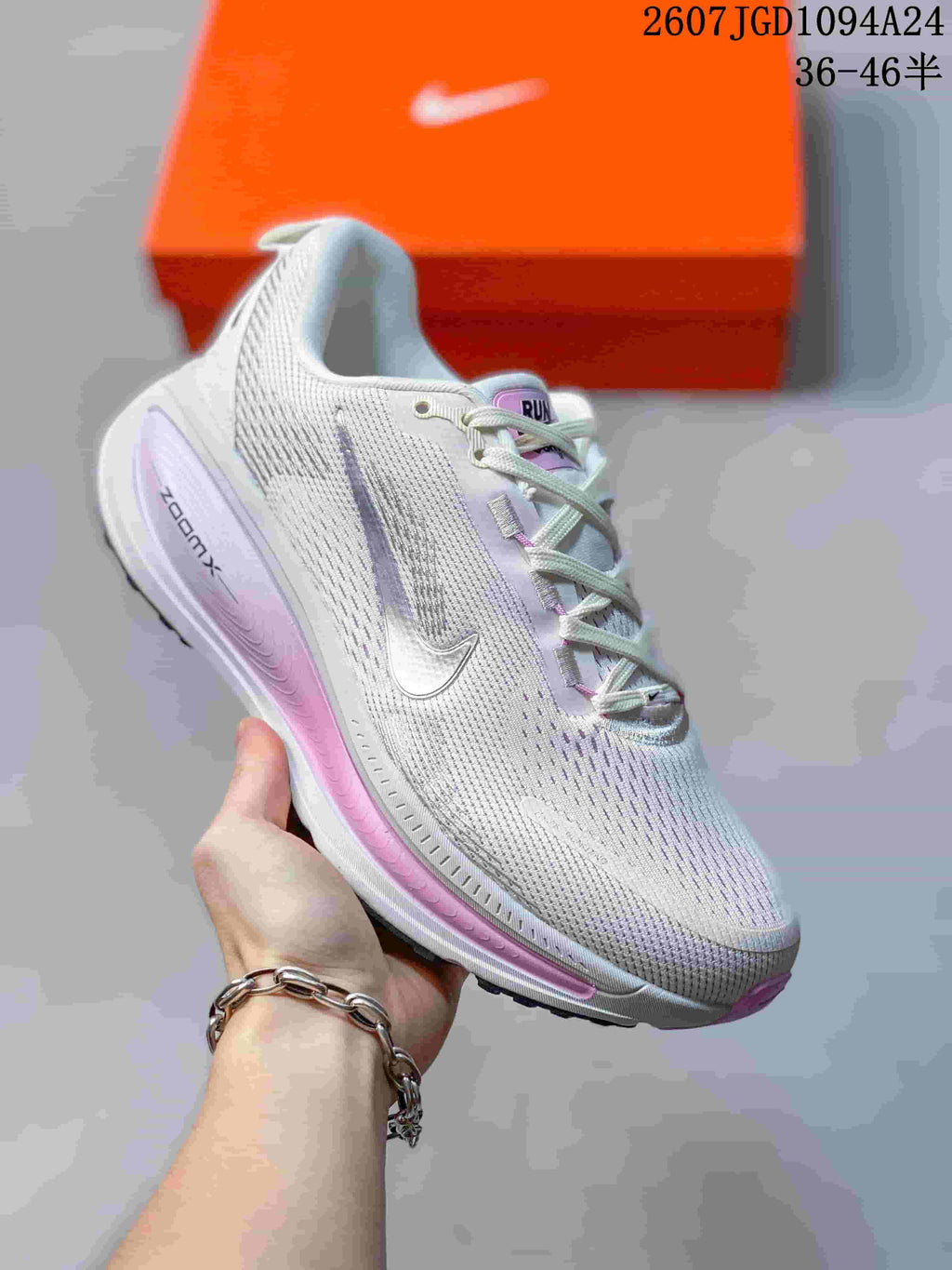 Angled side view of the sneaker showing the white upper, dark Swoosh, pink midsole detail, and ZOOMX branding.