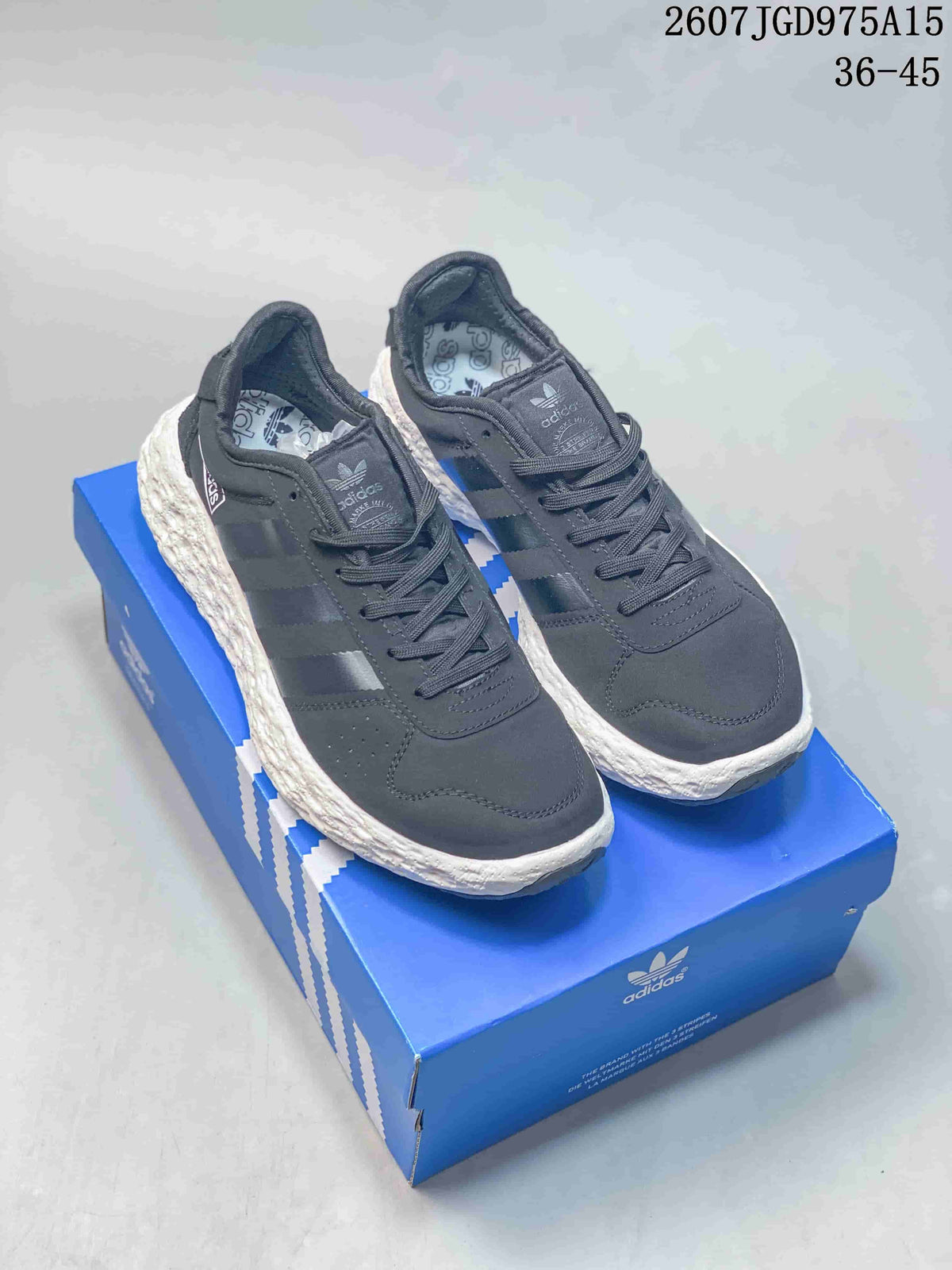 Pair of dark Adidas Originals low-top sneakers displayed on a blue shoe box, with a white textured sole.