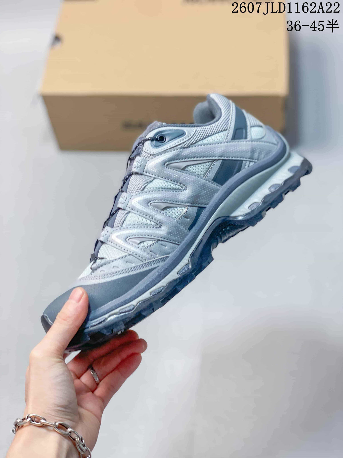 Side profile of the grey and silver low-top sneaker showing its layered upper and lugged outsole.