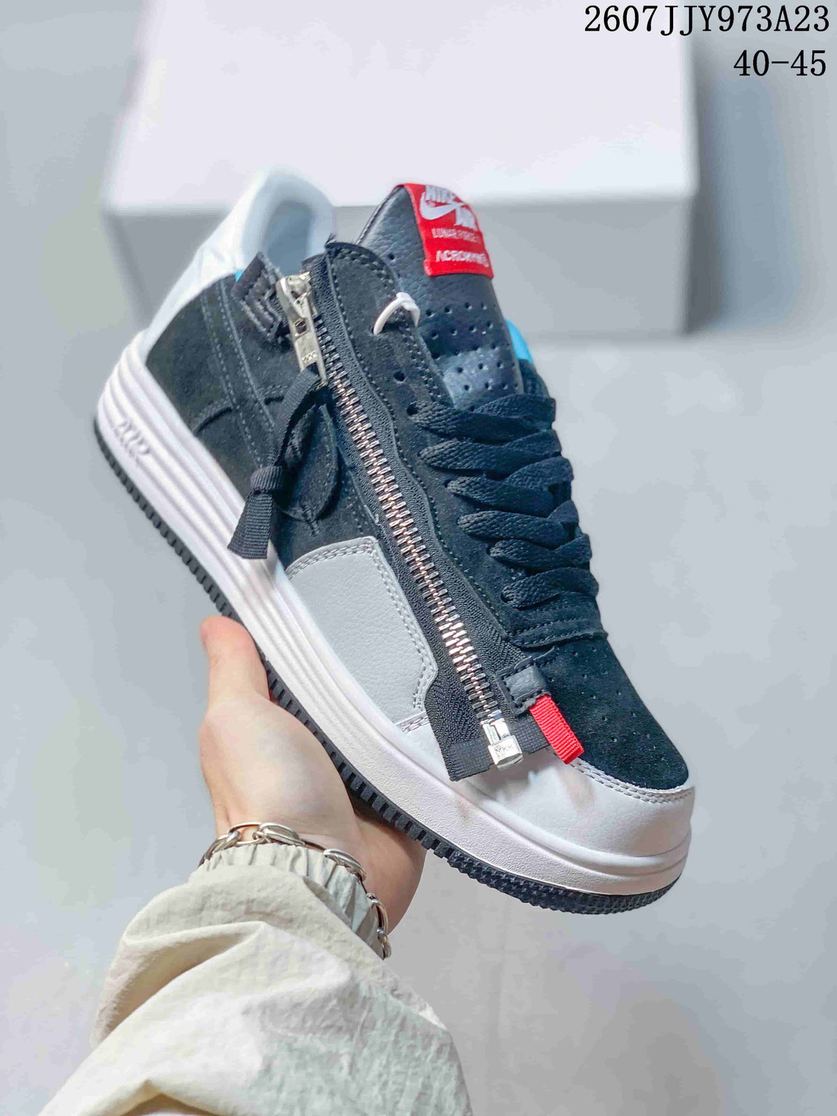 Angled side view highlighting the long metal zipper, red zipper pull, dark upper, white side panel, and white midsole.
