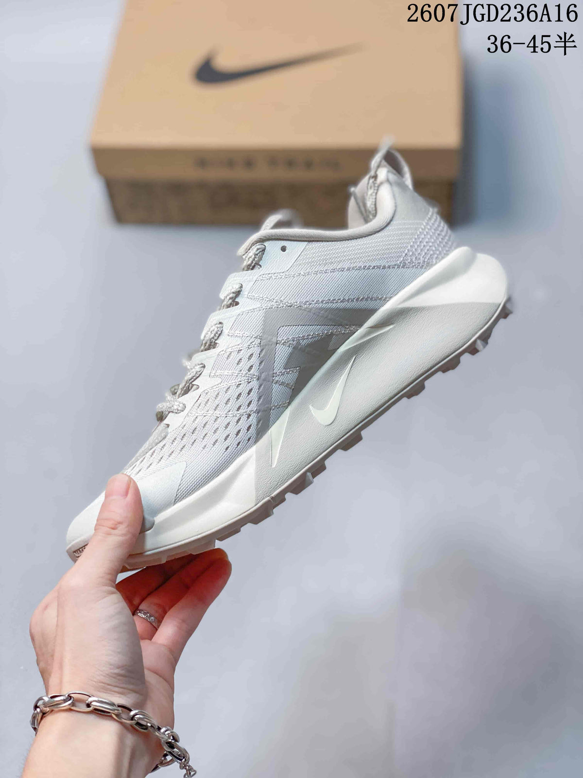 Side profile of the light white and gray trail running shoe showing the Swoosh, lace-up construction, mesh-style upper, and raised midsole.
