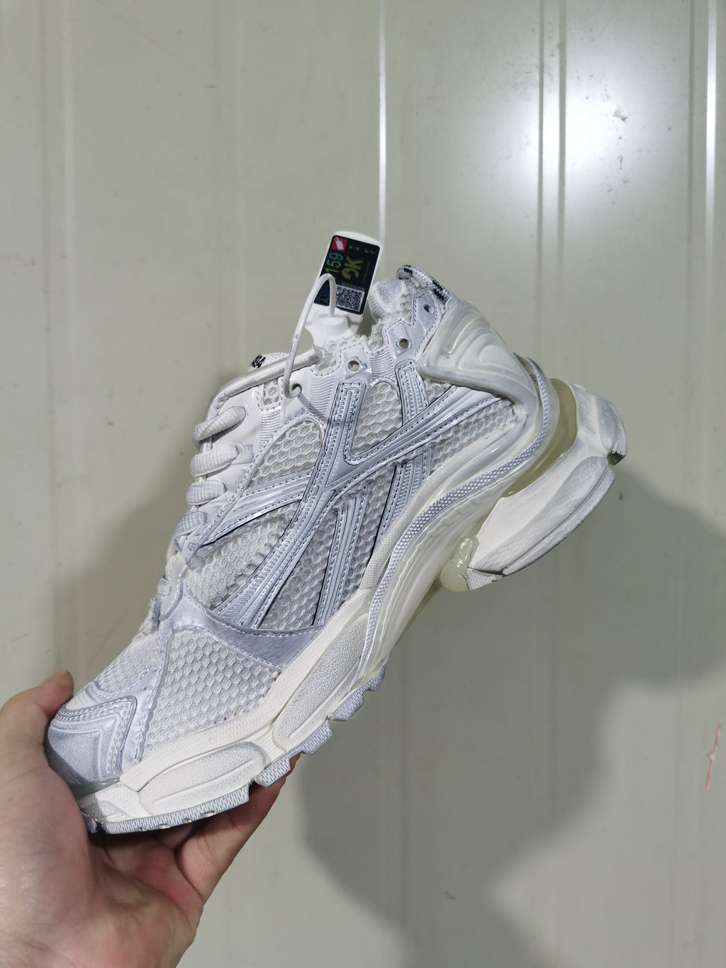 Rear three-quarter view of the white Runner sneaker, showing the layered heel structure, mesh panels, and translucent-looking midsole sections.