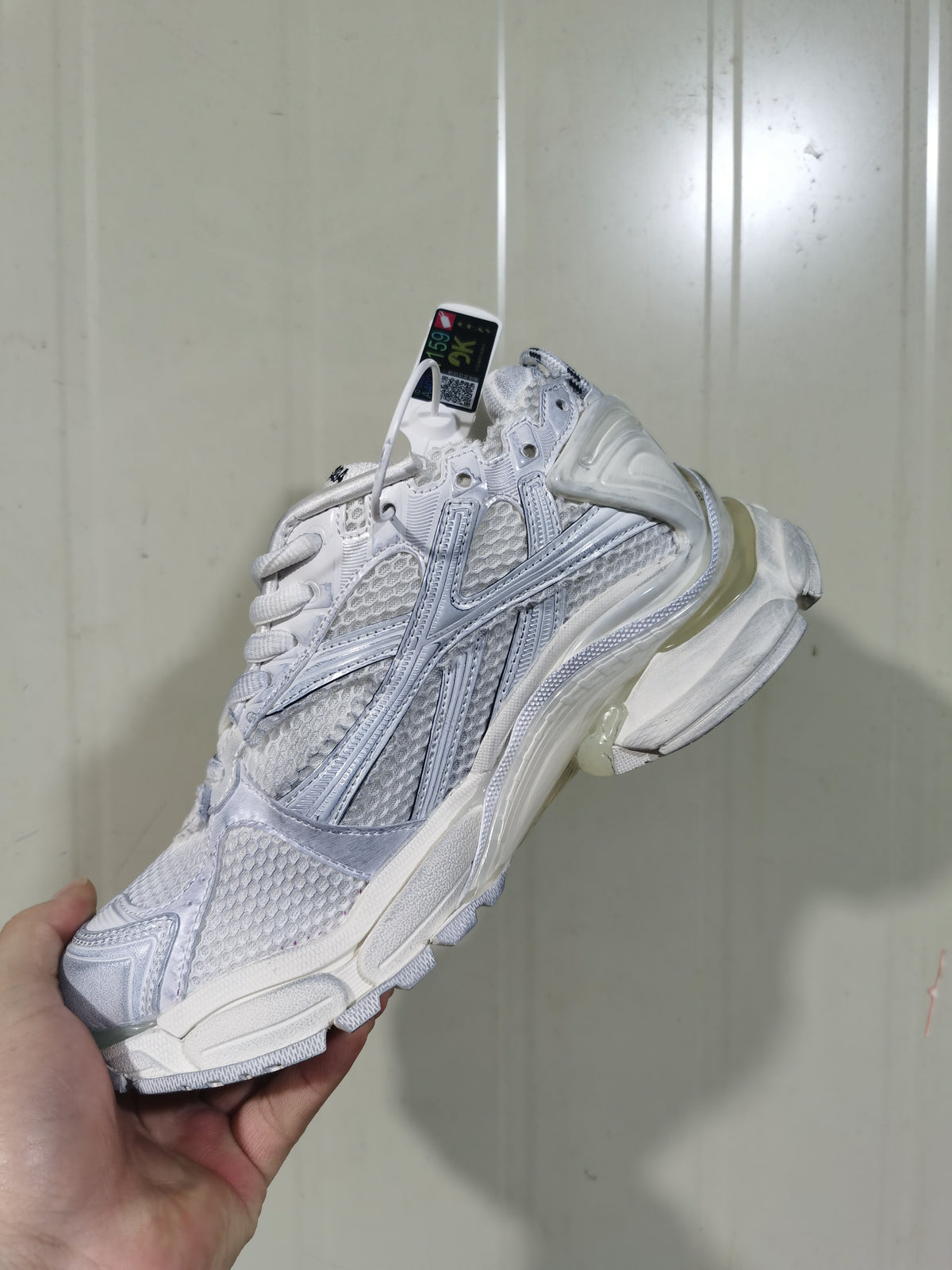 Rear three-quarter view of the white Runner sneaker, showing the layered heel structure, mesh panels, and translucent-looking midsole sections.