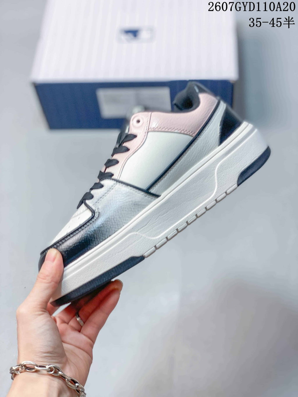 Side view of the low-top sneaker showing pink collar trim, contrasting overlays, and the raised sole.