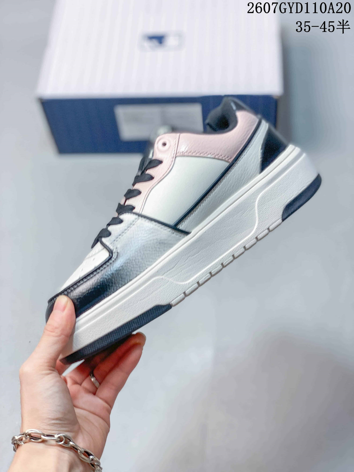 Side view of the low-top sneaker showing pink collar trim, contrasting overlays, and the raised sole.