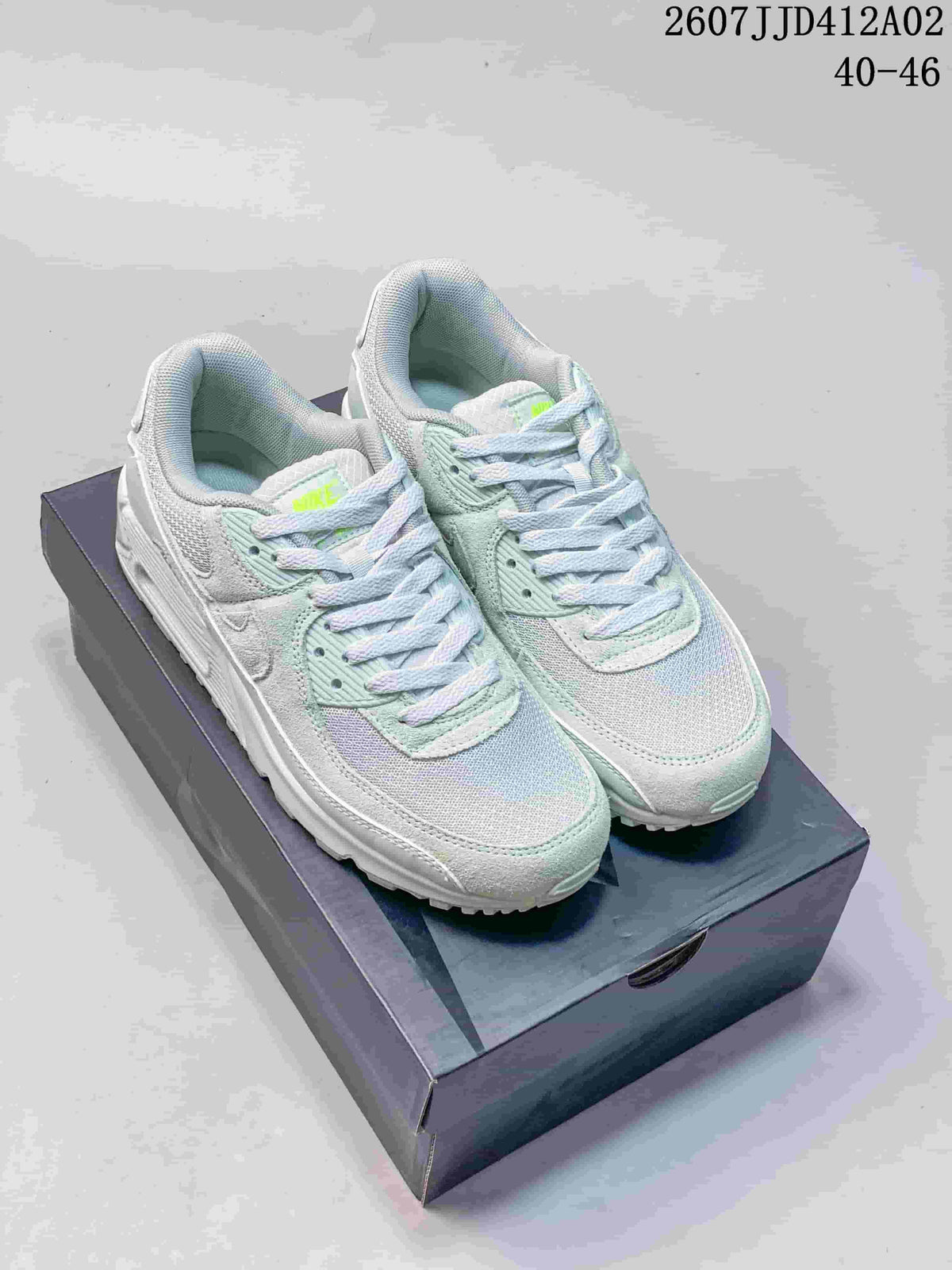 Pair of pale blue, mint, and white Nike Air Max 90 sneakers shown from the front on a shoe box.