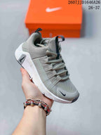 Angled side view of the gray and white Nike Free Metcon 7 children's sneaker with its lace-up design and patterned outsole.