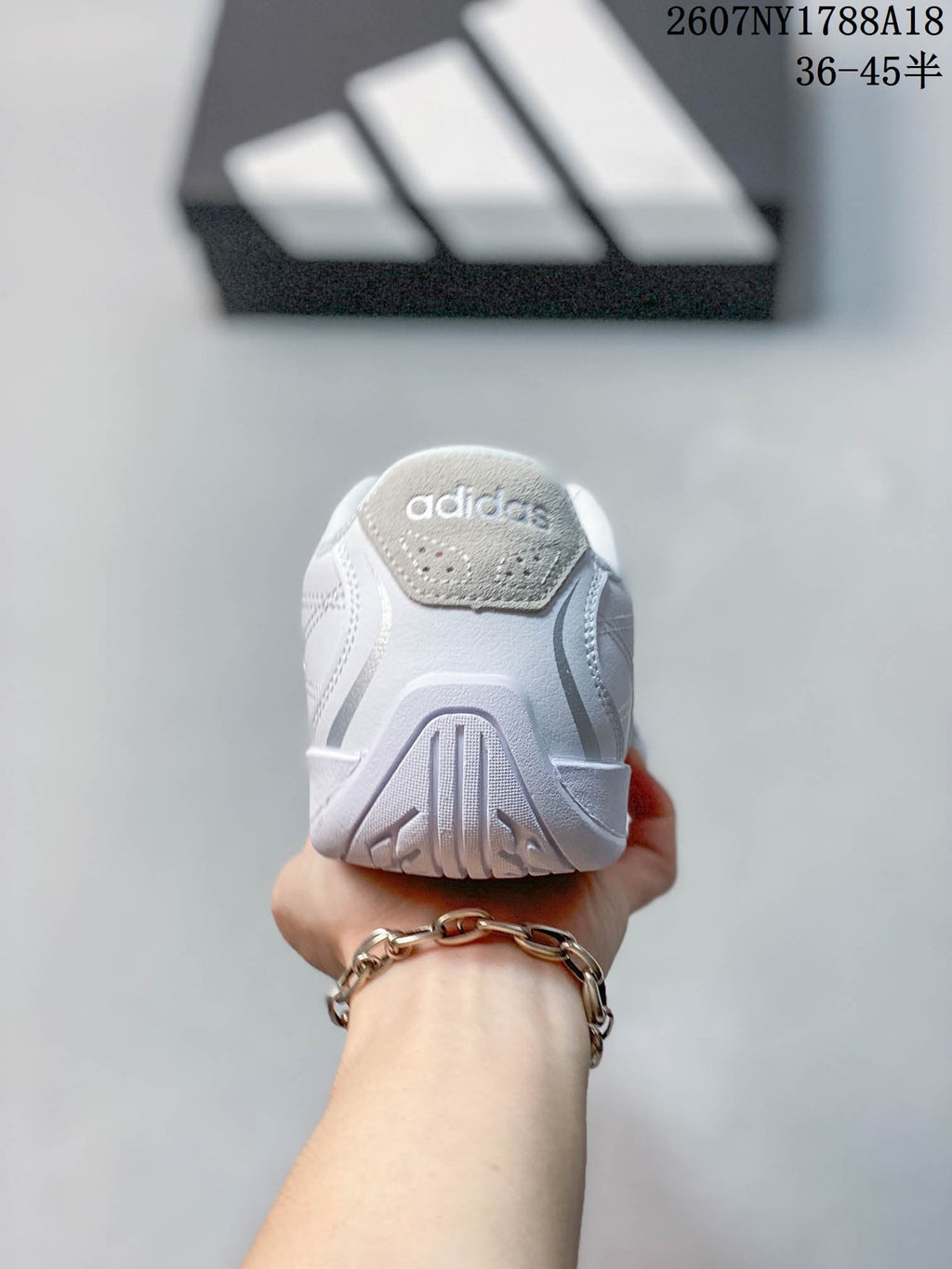 Rear view showing the padded heel area and outsole pattern of the white sneaker.