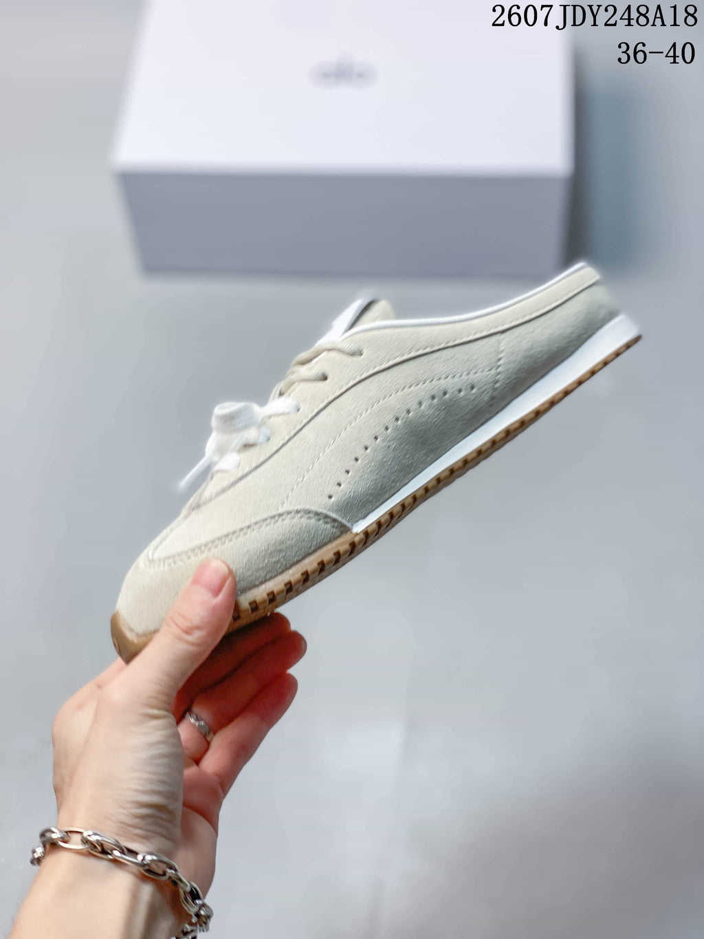 Side profile of a cream low-profile sneaker showing perforated detailing and the gum-colored outsole.