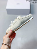 Side profile of a cream low-profile sneaker showing perforated detailing and the gum-colored outsole.