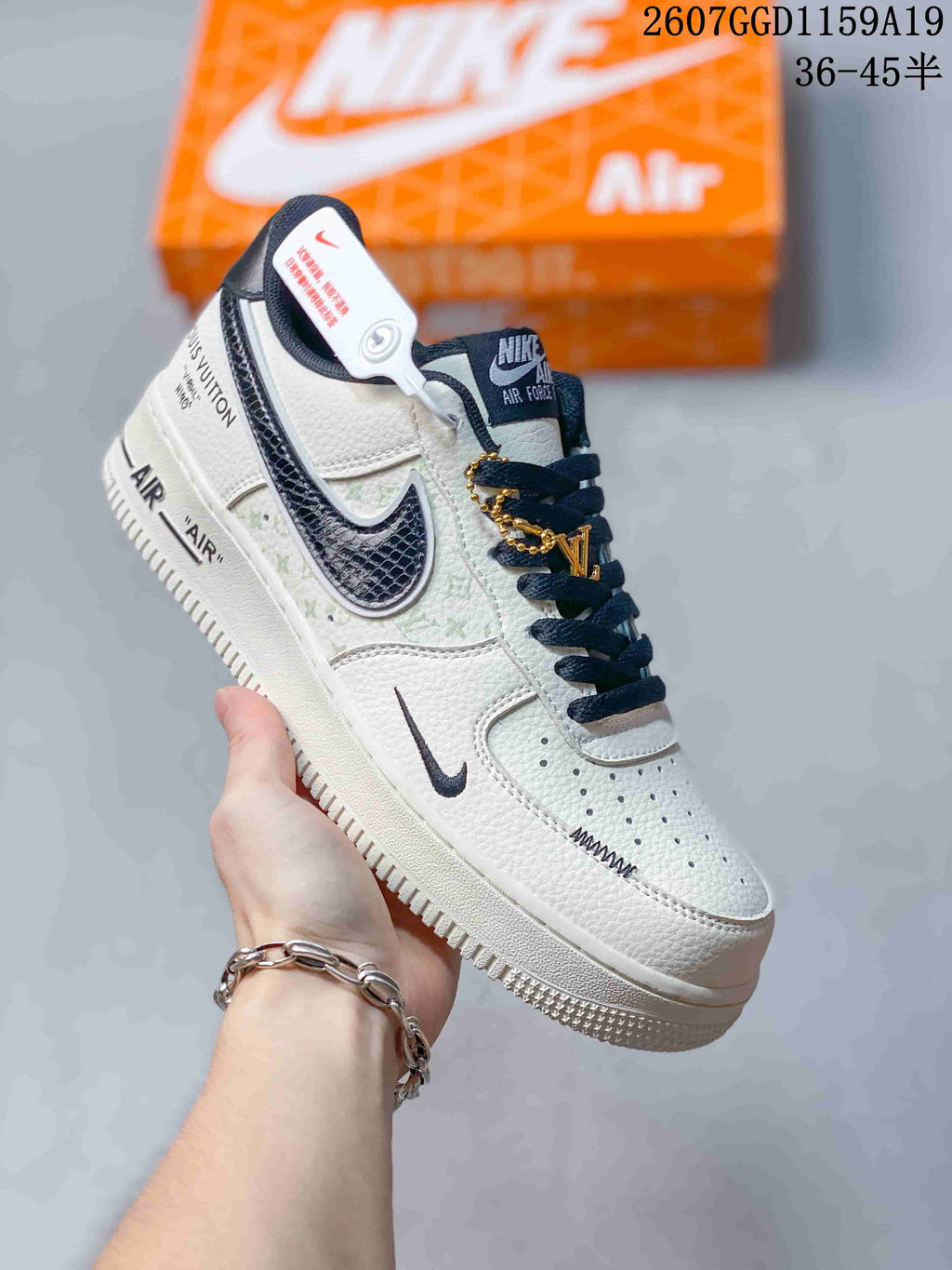 Angled side view of the white and black sneaker showing Nike Swoosh details, Air Force 1 tongue branding, decorative side lettering, and a gold-tone lace accessory.