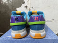 Rear view of white Nike Ja 1 shoes with blue and purple heel panels, green accents, and orange outsoles