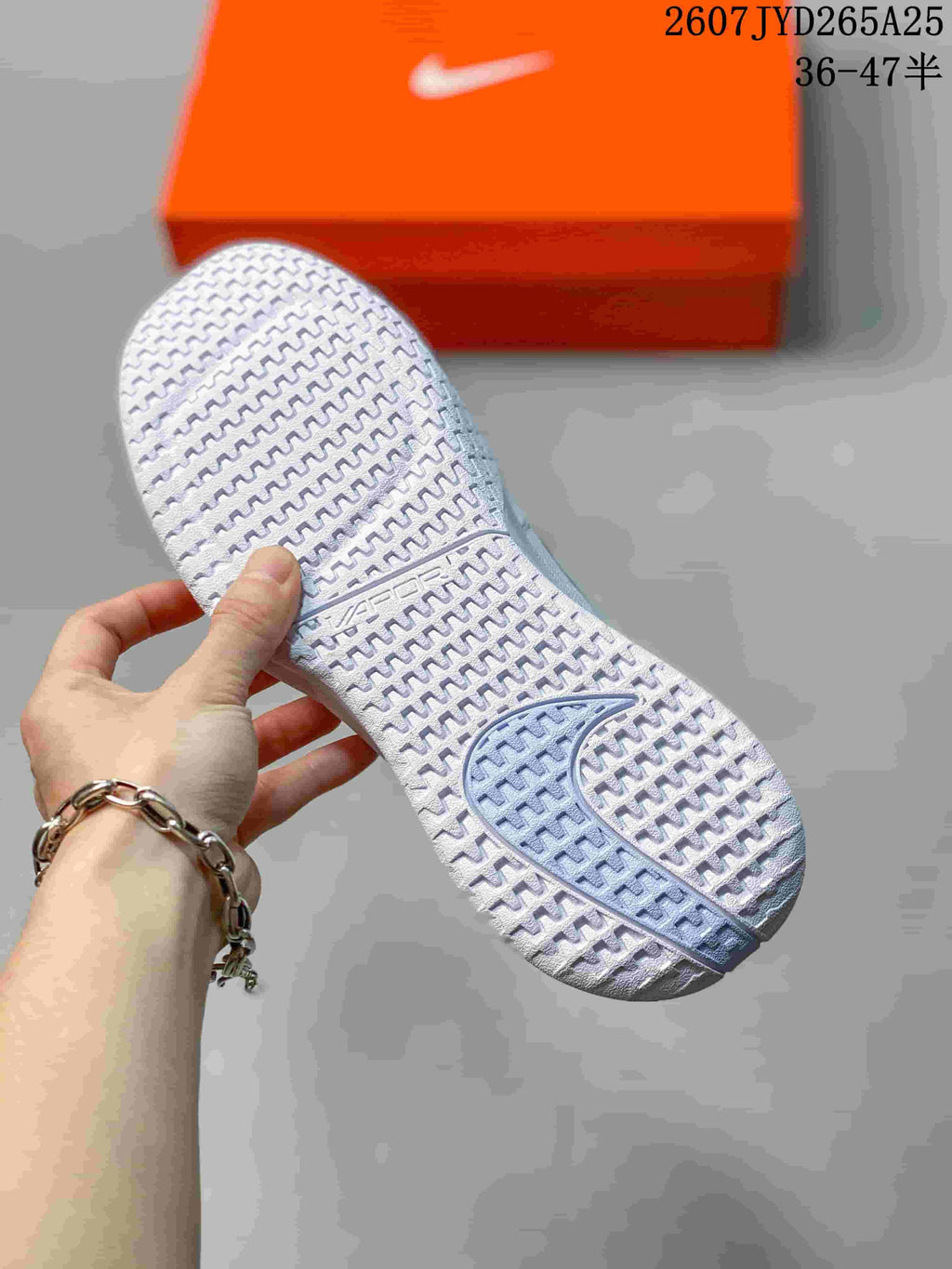 Close-up of the patterned outsole on a white tennis shoe.