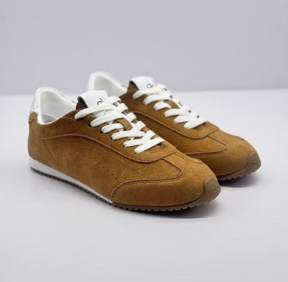 Front three-quarter view showing the rounded toes, brown uppers, white laces, and white midsoles.