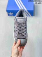 Front view of the grey sneaker showing the tonal laces, padded tongue, and ribbed shell toe.