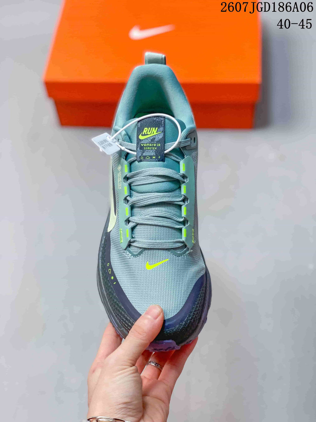 Top view of the gray lace-up sneaker showing the padded collar, tongue label, textile-style upper, and neon yellow accents.