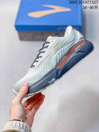 Side profile showing the patterned upper, Brooks branding, orange accent detail, and thick navy sole.
