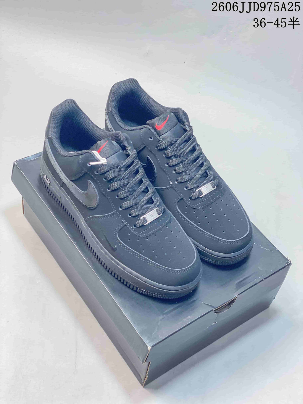 Pair of black Nike Air Force 1 low-top sneakers displayed on a shoe box, with style code JD975A25 and size range text visible above.