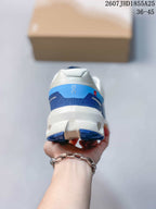 Rear view of the white and blue sneaker showing the padded heel collar, layered heel details, and segmented outsole.