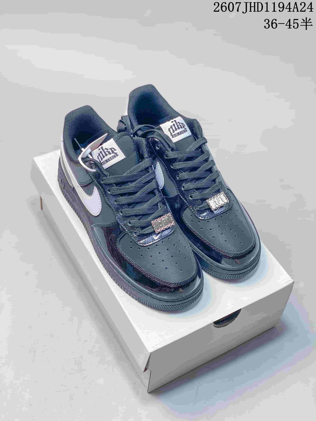 Pair of black and white low-top sneakers shown on a white shoebox, with contrasting Swoosh panels and lace details.
