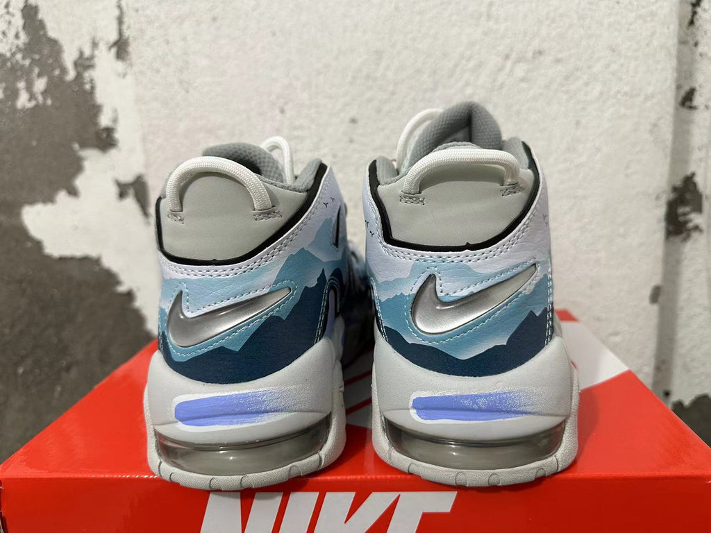 Rear view of Nike Air More Uptempo sneakers with blue graphic heel panels and metallic Swooshes