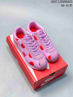 Pair of pink and red Nike Classic Cortez sneakers displayed on a red Nike shoebox.