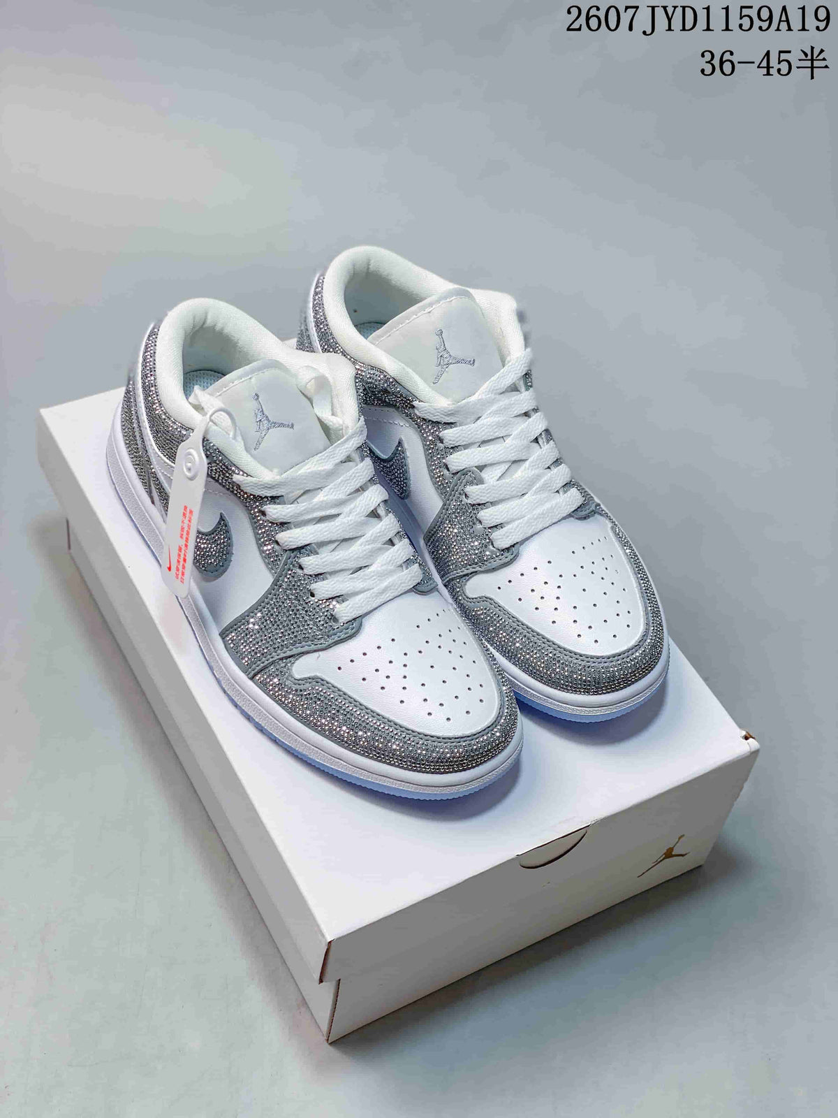 Pair of white and silver low-top Jordan sneakers displayed on a shoebox, with the style code 2607JYD1159A19 and size range 36–45 shown above.