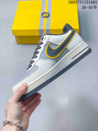 Side view highlighting the gray swoosh-shaped panel with yellow trim and white upper.