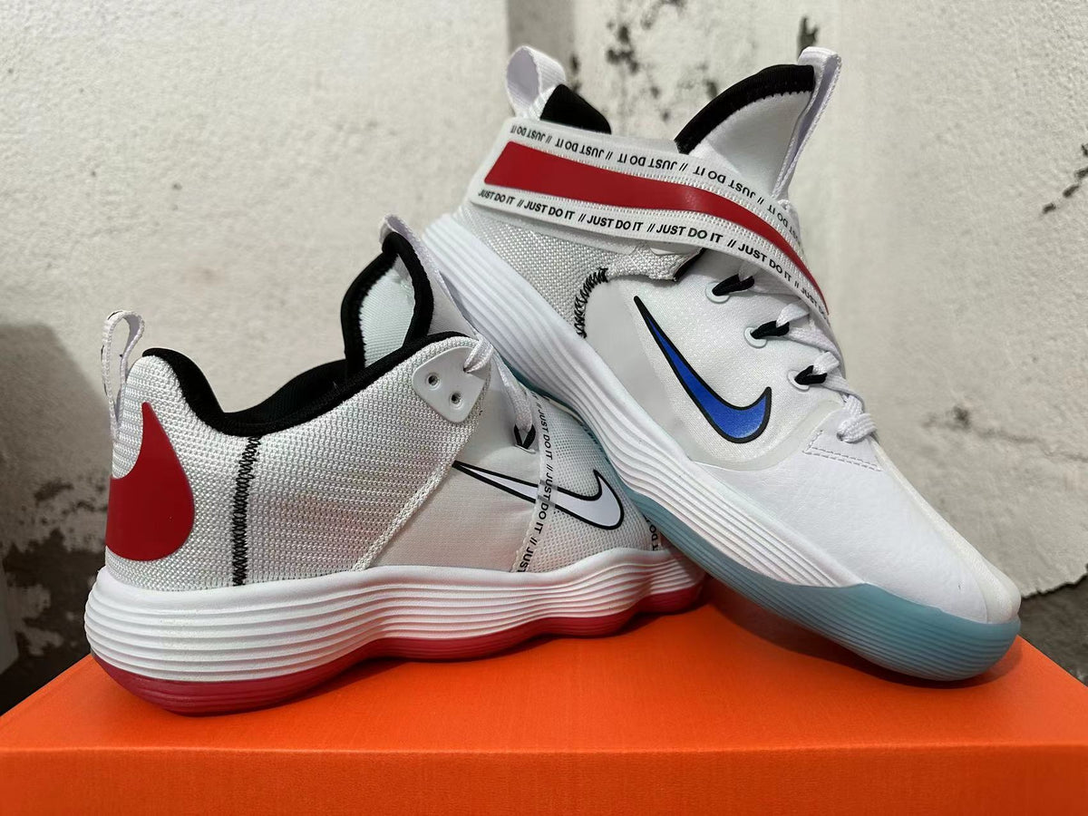 Pair of white Nike sneakers with red heel details, printed straps, and colored translucent outsoles.