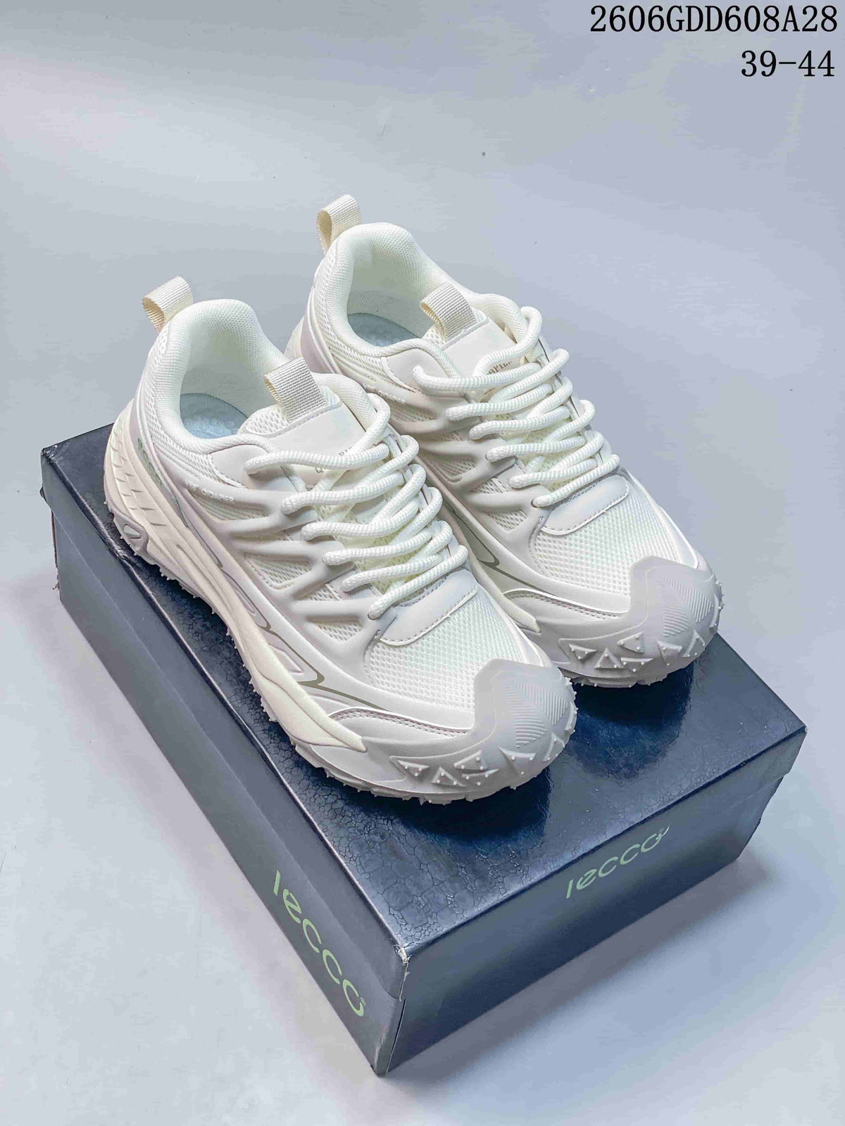 White lace-up sneakers shown from above on a branded shoe box.