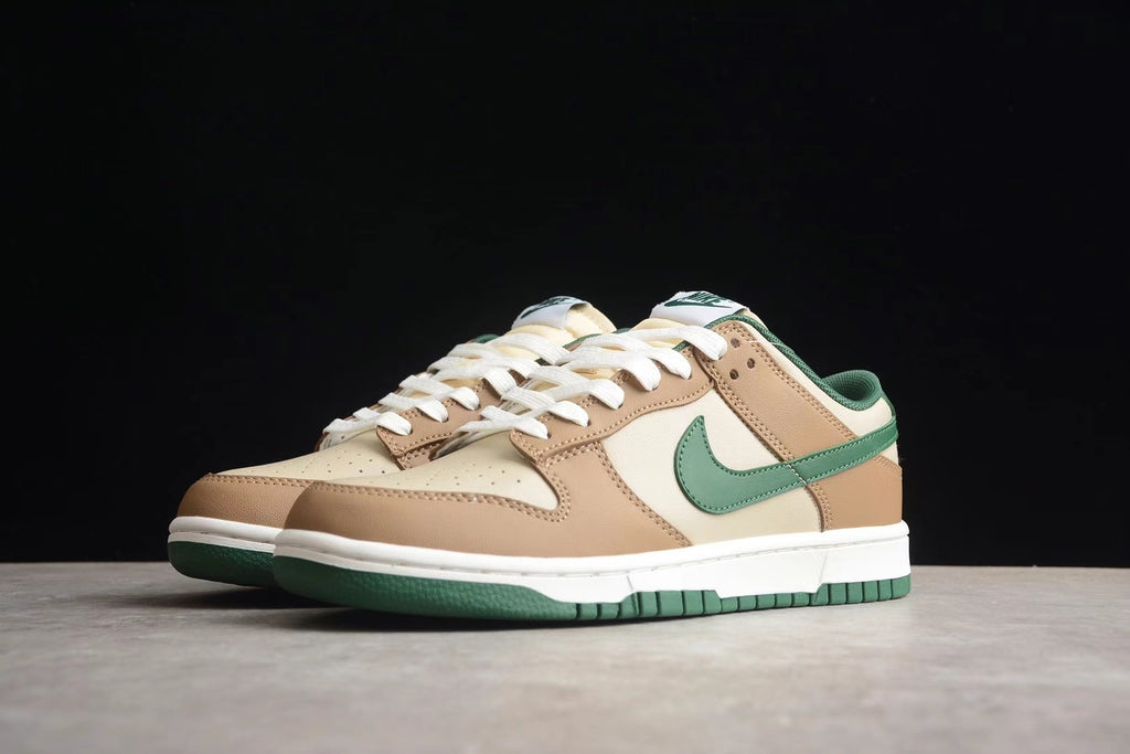 Front three-quarter view of the pair showing the brown and cream upper, green Swoosh, white midsole, and green outsole.