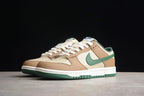 Front three-quarter view of the pair showing the brown and cream upper, green Swoosh, white midsole, and green outsole.
