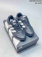 Pair of dark adidas Adipista low-top trainers with white side stripes displayed on a shoebox.