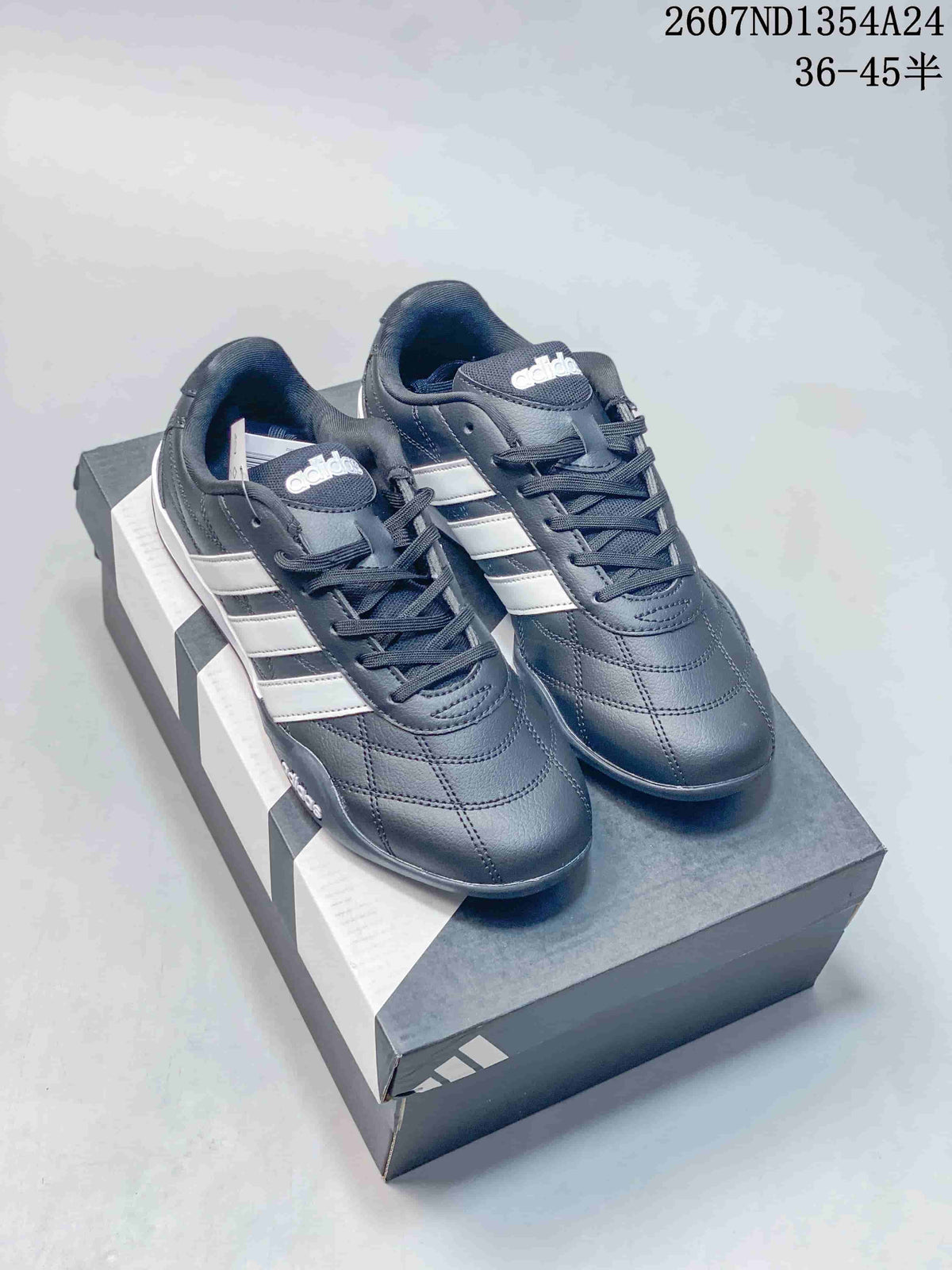 Pair of dark adidas Adipista low-top trainers with white side stripes displayed on a shoebox.
