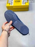 Close view of the patterned rubber outsole on a blue sneaker, with the yellow shoe box in the background.