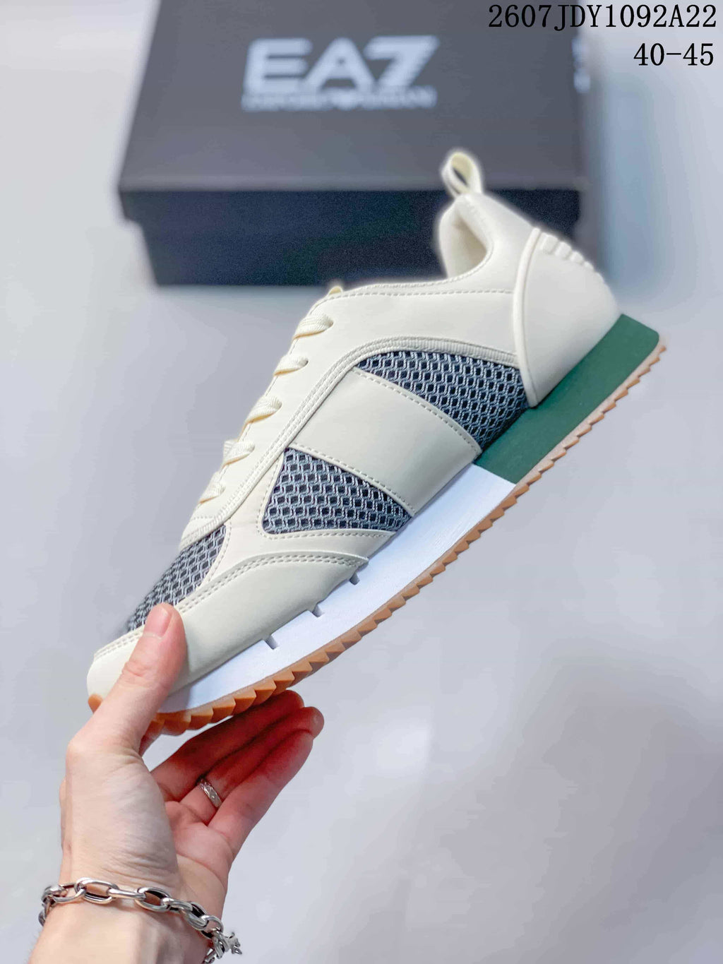 Side view of an off-white EA7 sneaker with gray mesh panels, green heel and midsole accents, and a textured outsole edge.
