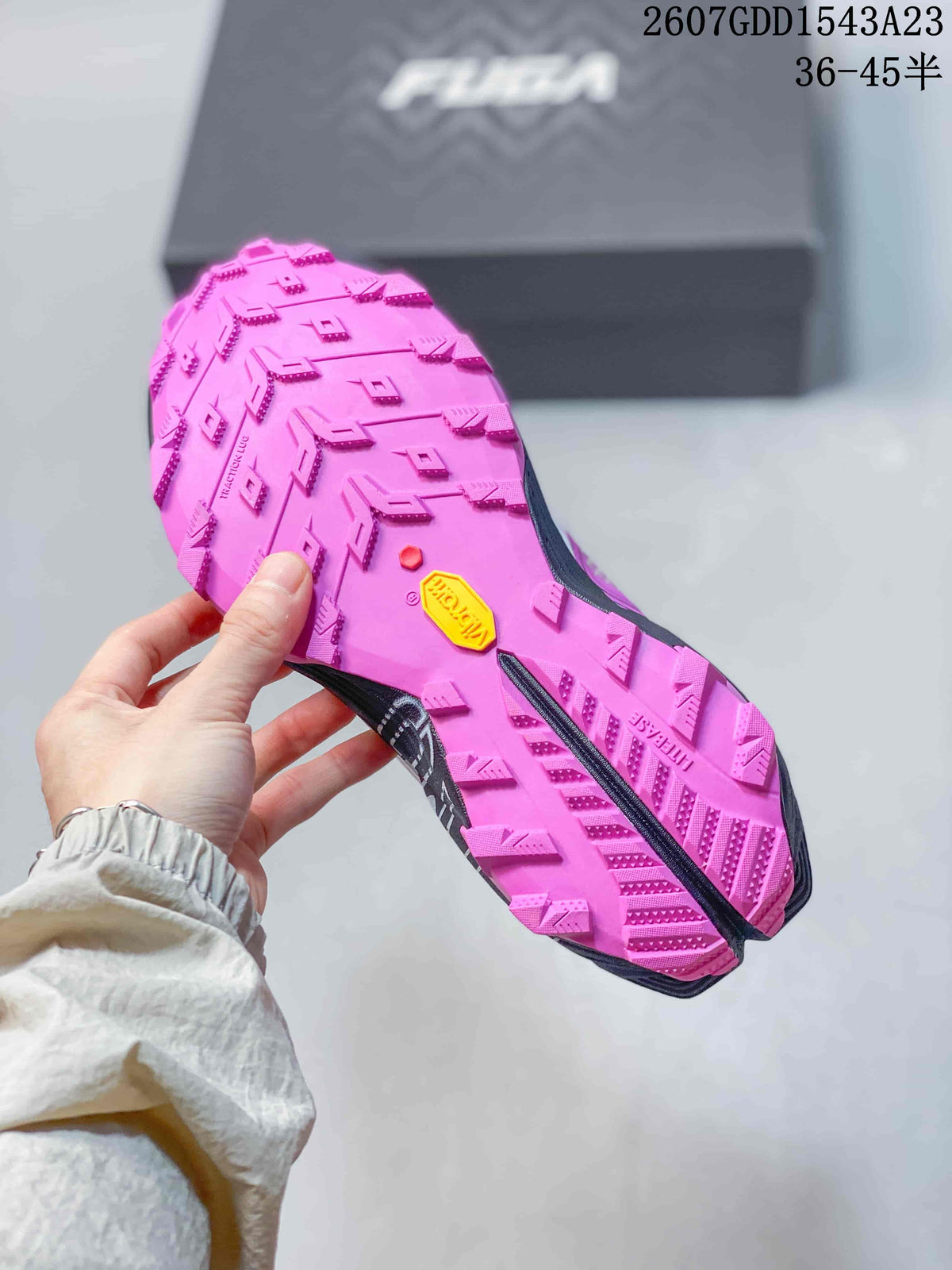 Close view of the pink outsole with deep directional tread and a yellow outsole insert.