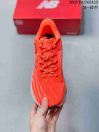 Top view of the orange running shoe with matching patterned laces and a structured tongue.