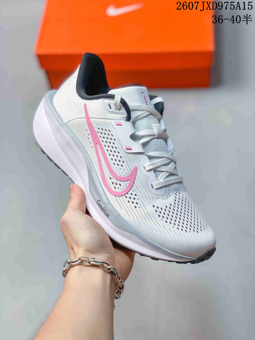 Angled side view of the white Nike Quest 6 shoe with pink branding and black outsole accents.