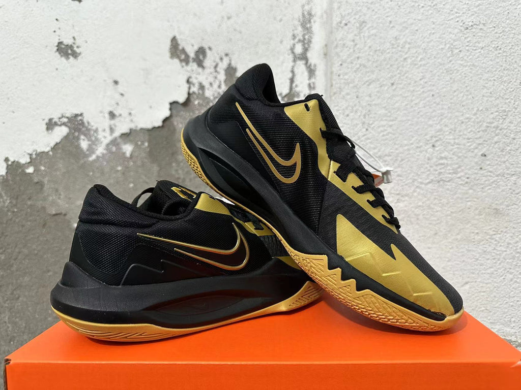 Pair of black and gold Nike basketball sneakers shown from the side