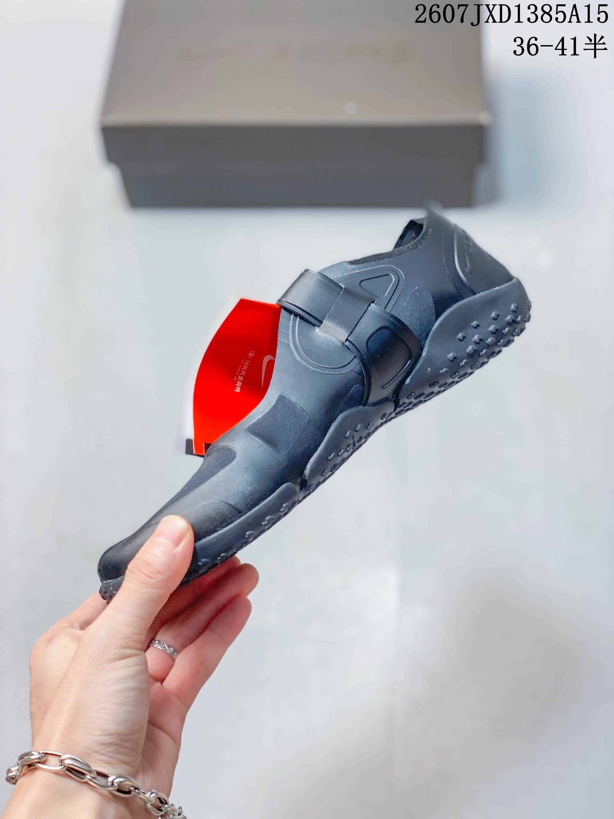 Side view of a black Nike Air Rift split-toe shoe showing the forefoot strap and layered upper.