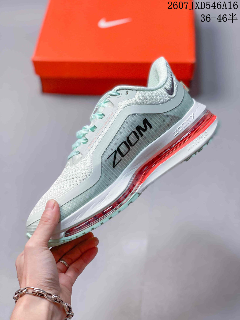 Side profile showing the pale mint upper, large Zoom graphic, layered midsole, and red cushioning unit.